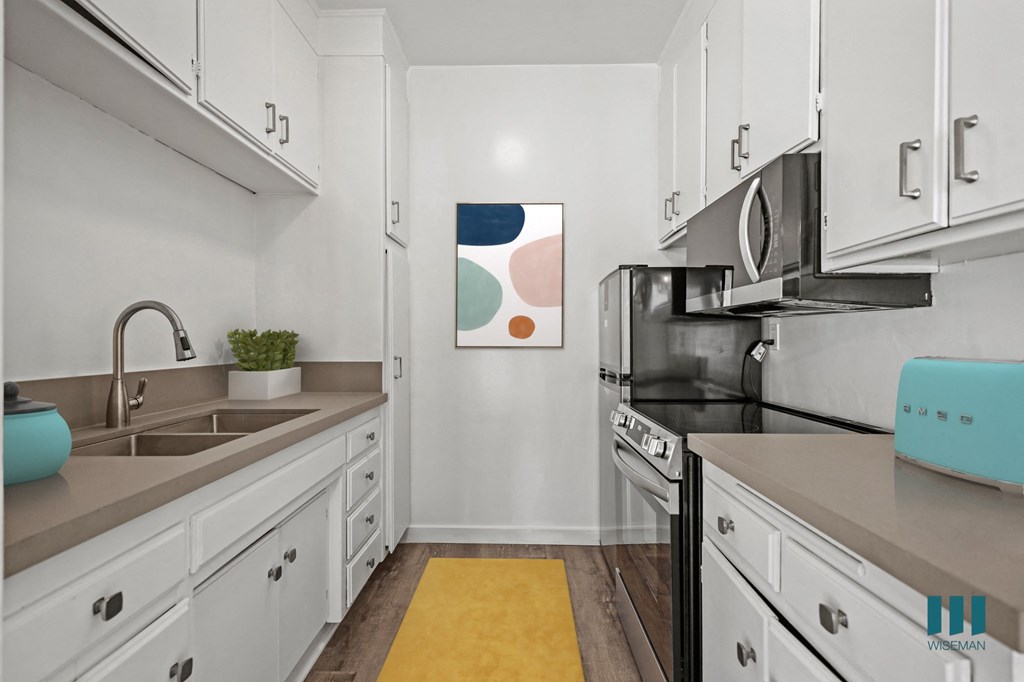 A kitchen with white cabinets and a yellow rug on the floor.