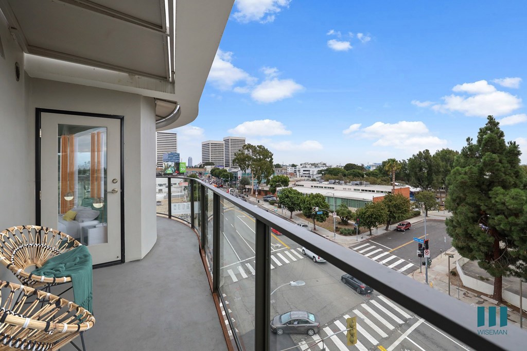 A balcony with a chair and a view of a city street.