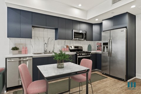 a kitchen with stainless steel appliances and a table with pink chairs