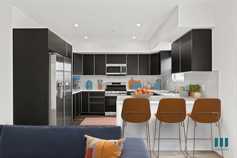 A modern kitchen with black cabinets and a blue couch.