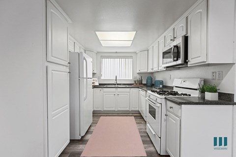 a white kitchen with white cabinets and a pink rug