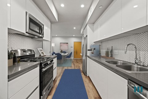 a kitchen with white cabinets and stainless steel appliances and a blue rug