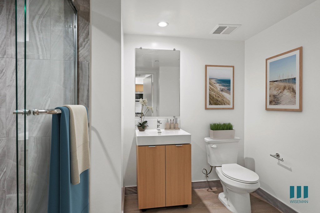 A bathroom with a white toilet and a sink with a cabinet underneath it.
