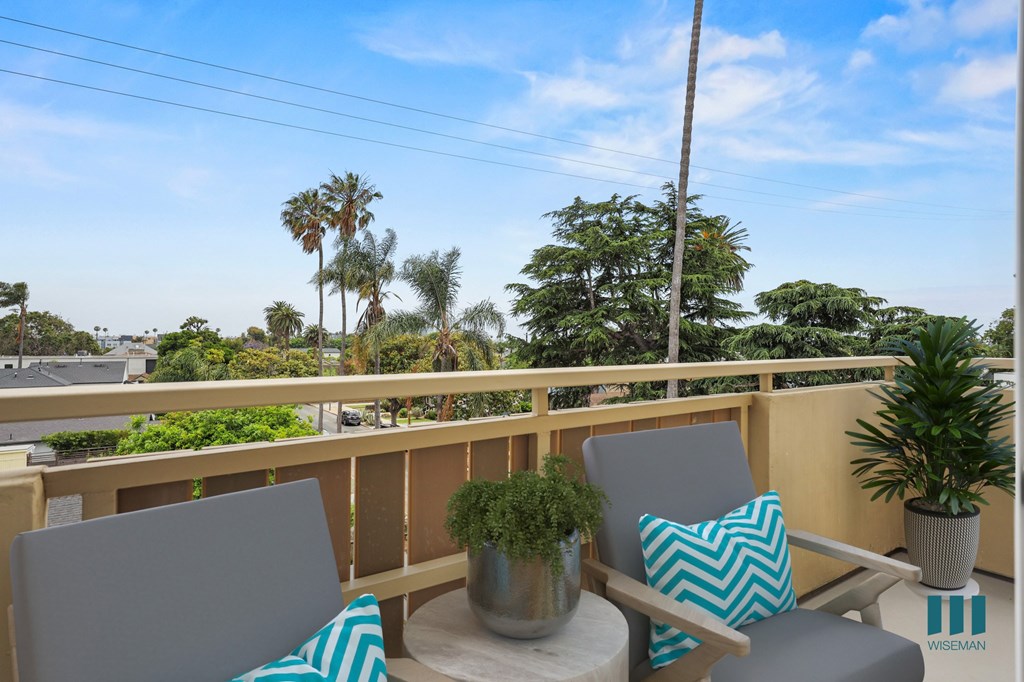 A balcony with two chairs and a table with a plant on it.