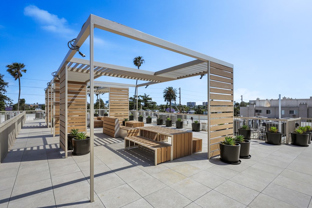 A wooden pergola with a bench and potted plants.