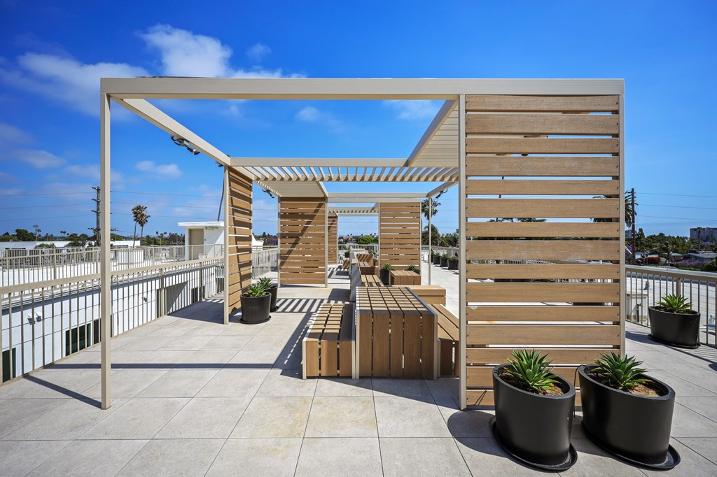 A wooden pergola with a bench and potted plants.