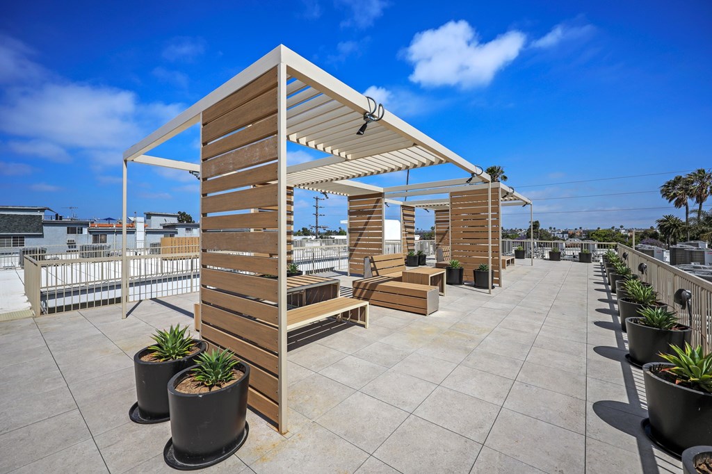 A wooden pergola with a bench and potted plants on a rooftop.