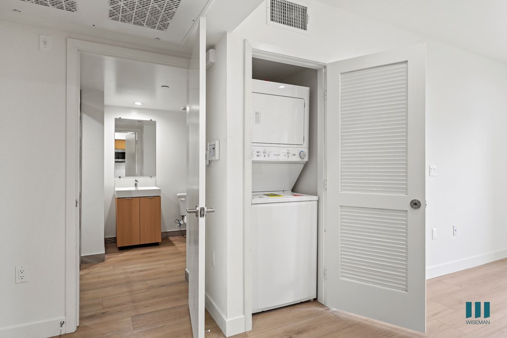 A white bathroom with a white fridge and a white door.