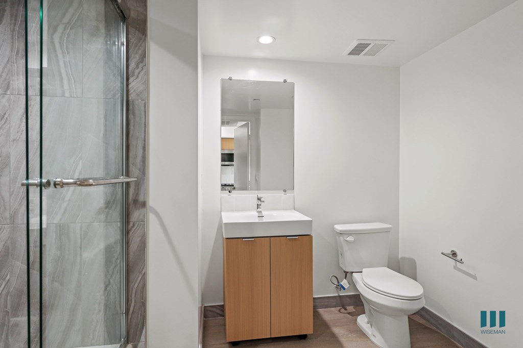A bathroom with a toilet, sink, and shower.