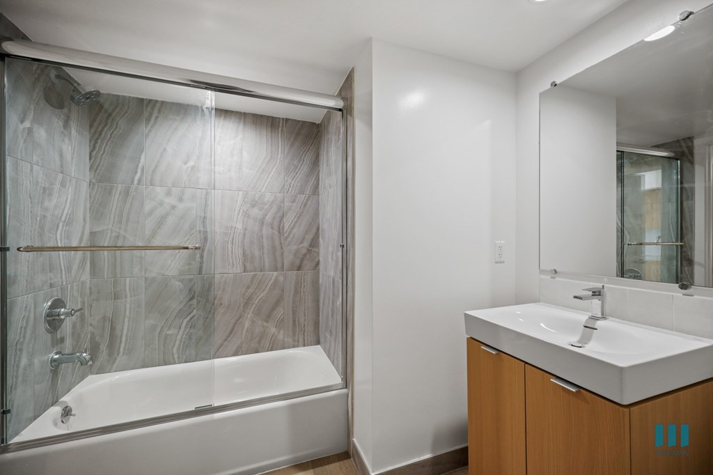 A modern bathroom with a marble tile shower and a white bathtub.
