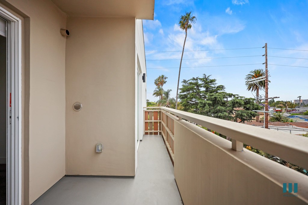 A balcony with a view of a pool and palm trees.