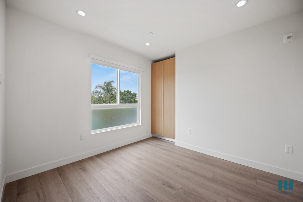 A room with a wooden floor and a window with a view of trees.
