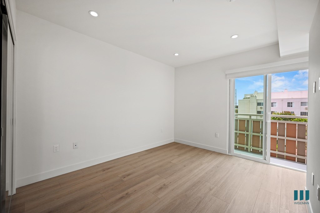 A large empty room with wooden floors and white walls.