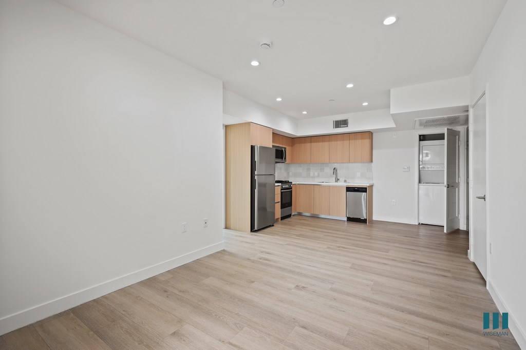 A kitchen with white walls and wooden floors is shown.