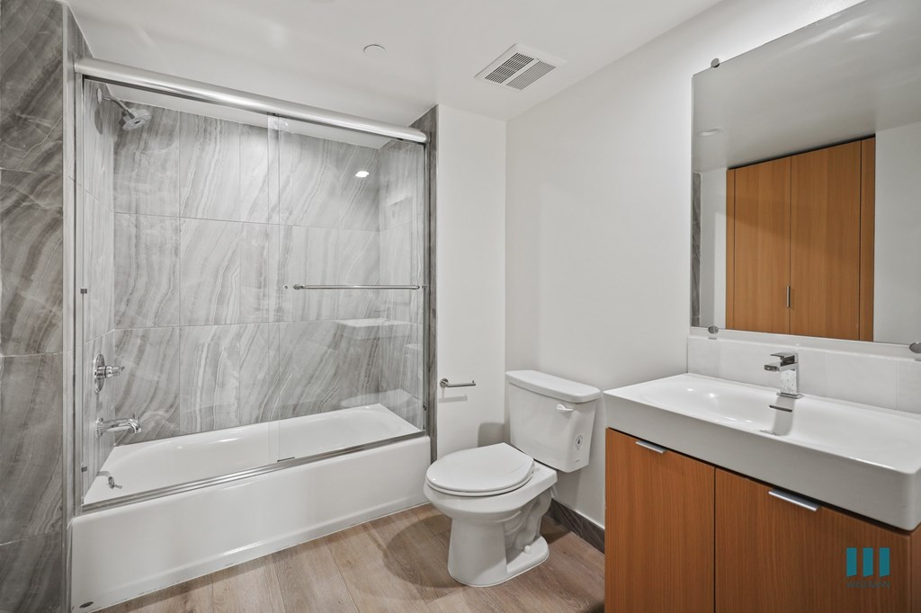 A modern bathroom with a marble wall and a walk-in shower.