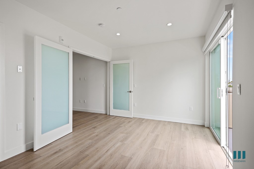A room with white walls and wooden flooring with two glass doors.