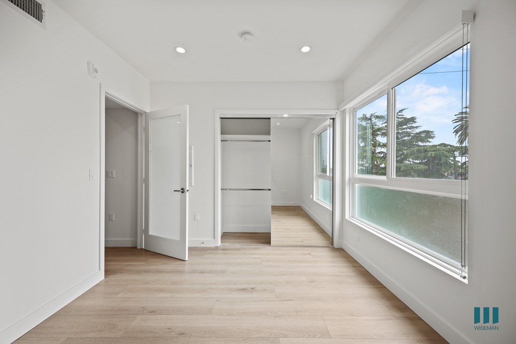 A spacious room with a kitchen area and a view of the outdoors through the windows.