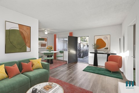 A living room with a green couch and a painting on the wall.