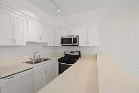 A kitchen with white cabinets and appliances.