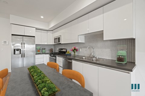 A modern kitchen with a long table and chairs.
