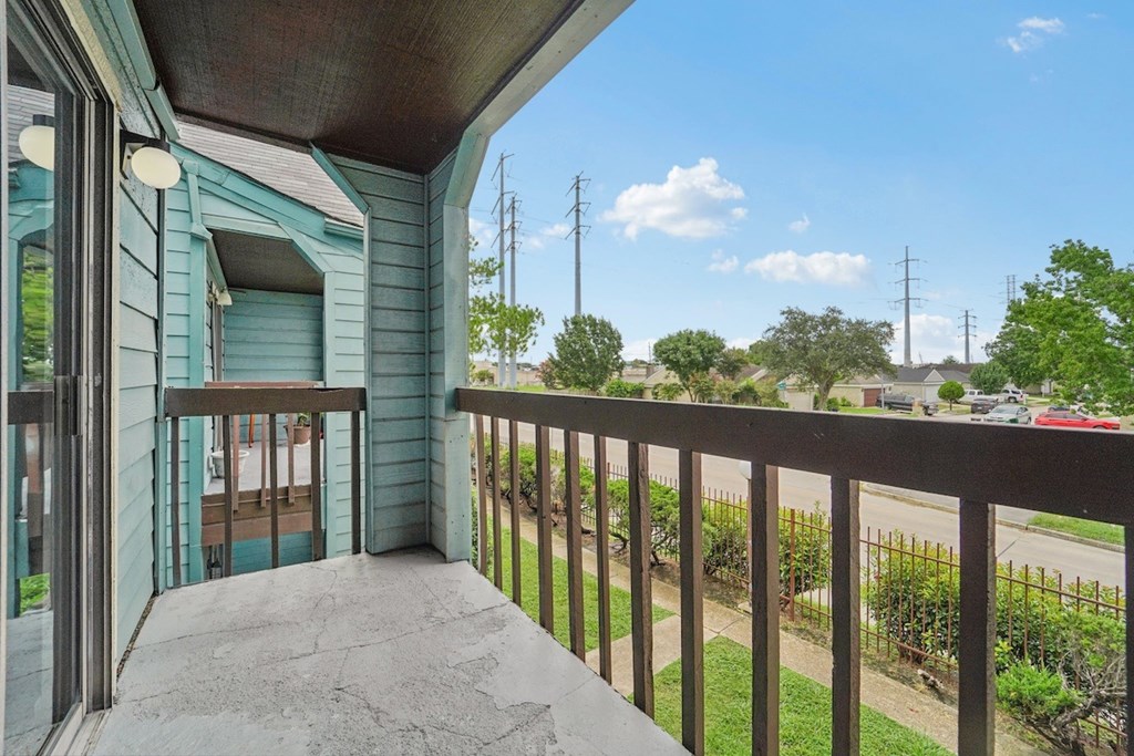 A balcony with a view of the street and houses.