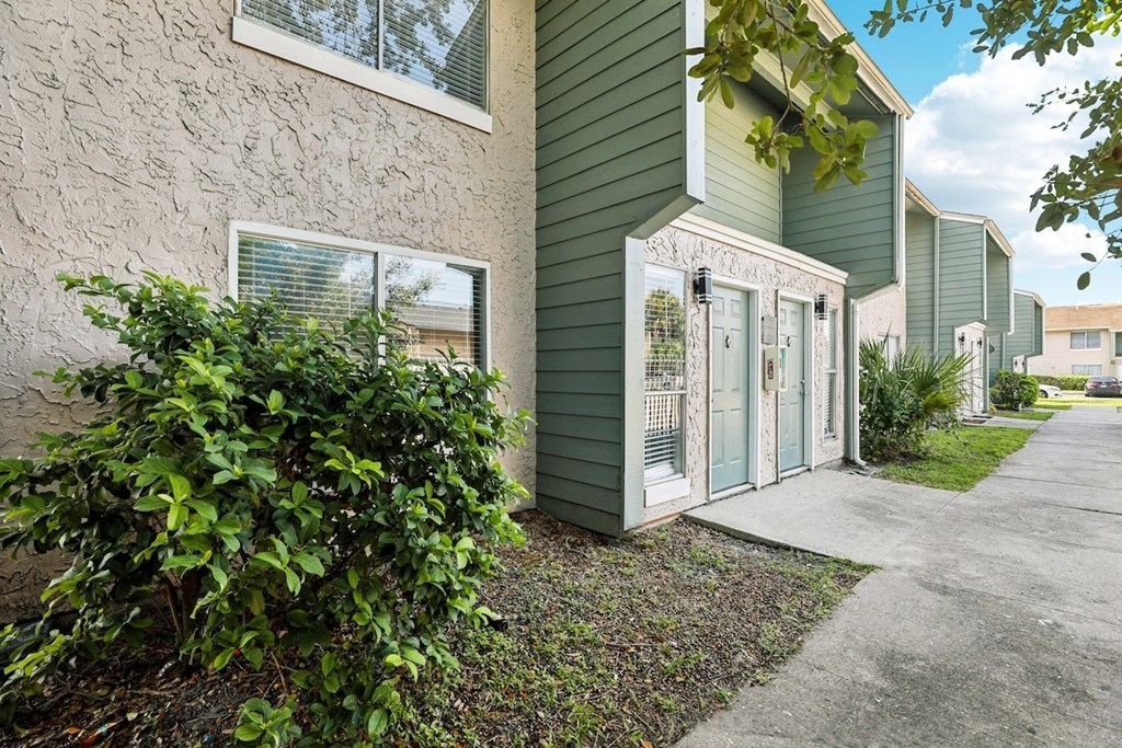 A green house with a white door and window.