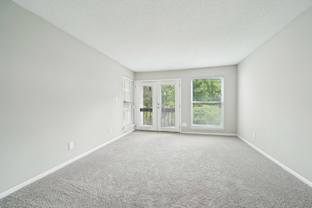 A room with a carpeted floor and a sliding glass door.at Hills at Hoover Apartments, Alabama