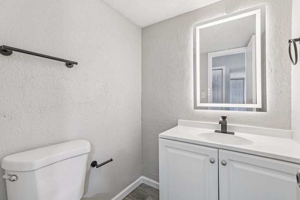 A white bathroom with a toilet, sink, and mirror.