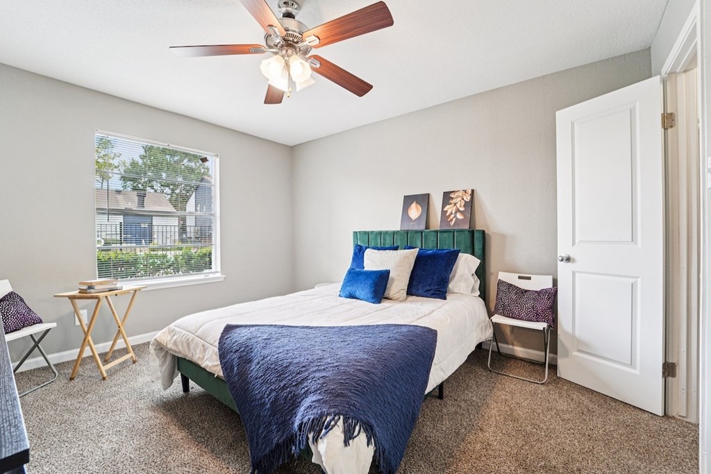 A bedroom with a bed, a chair, and a window.