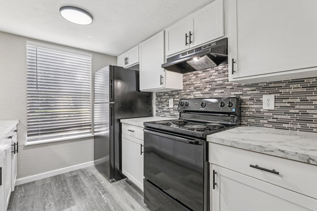 A kitchen with black appliances and white cabinets.