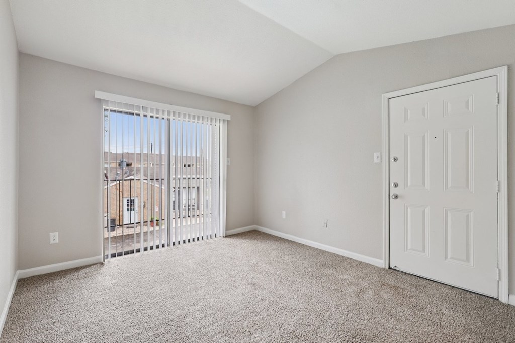 A room with a white door and a window with a view of a building outside.