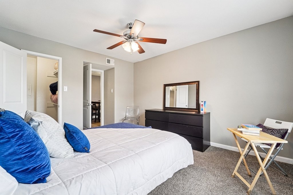 A bedroom with a bed, desk, and chair.
