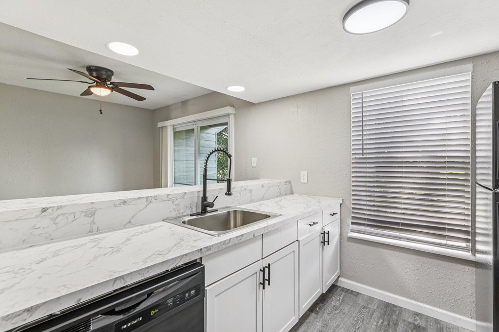 A kitchen with a marble countertop and white cabinets.