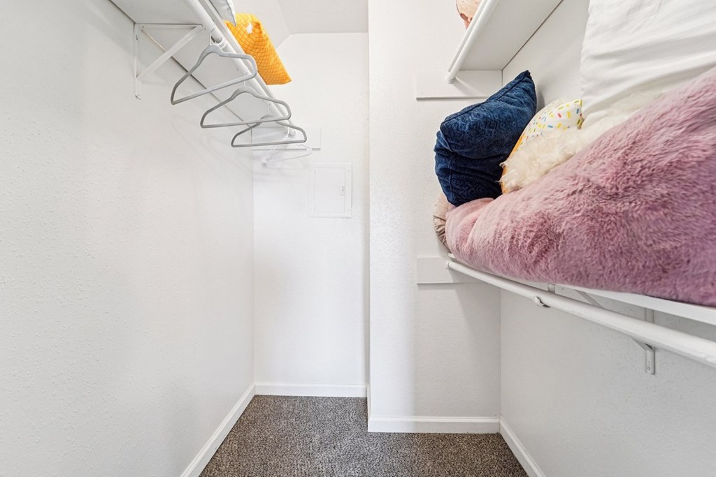 A small bedroom with a bed on the right and a hanger on the left.