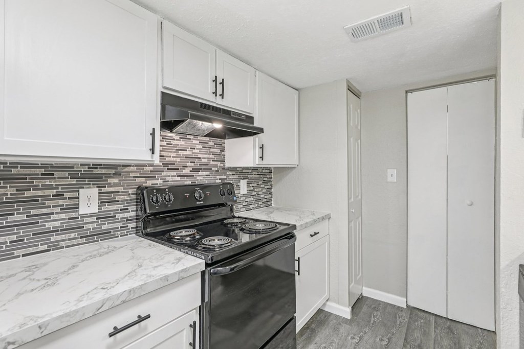 A kitchen with a black stove top oven and white cabinets.