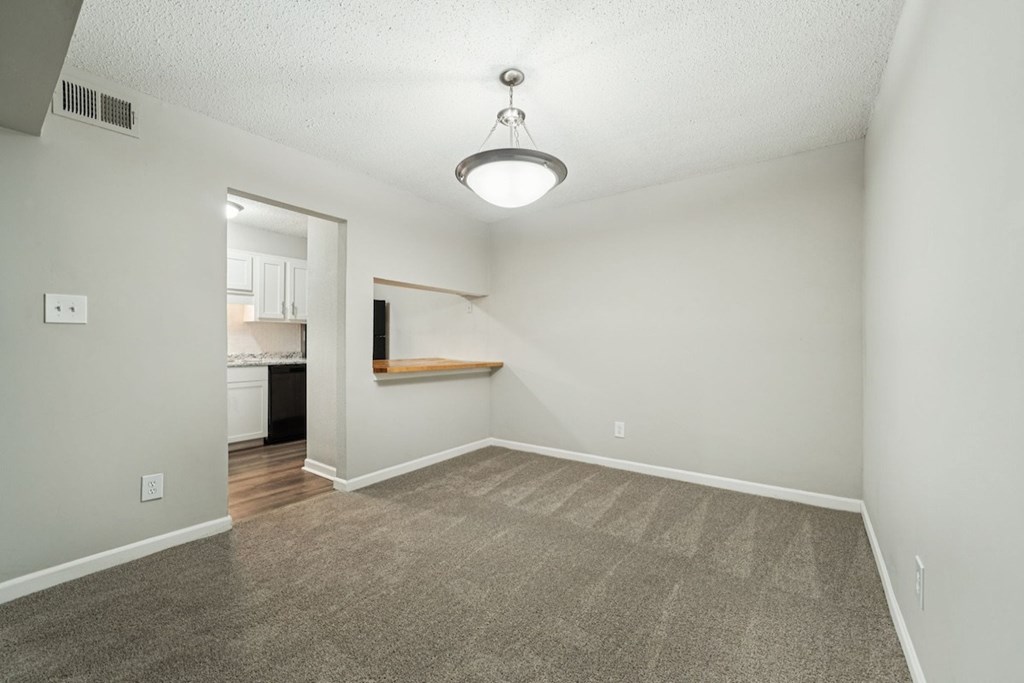 A room with a carpeted floor and a light fixture hanging from the ceiling.at Hills at Hoover Apartments, Alabama, 35216