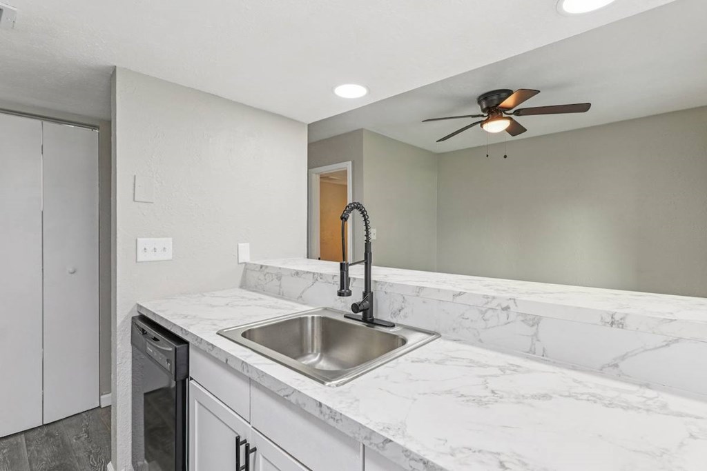 A kitchen with a marble countertop and a ceiling fan.