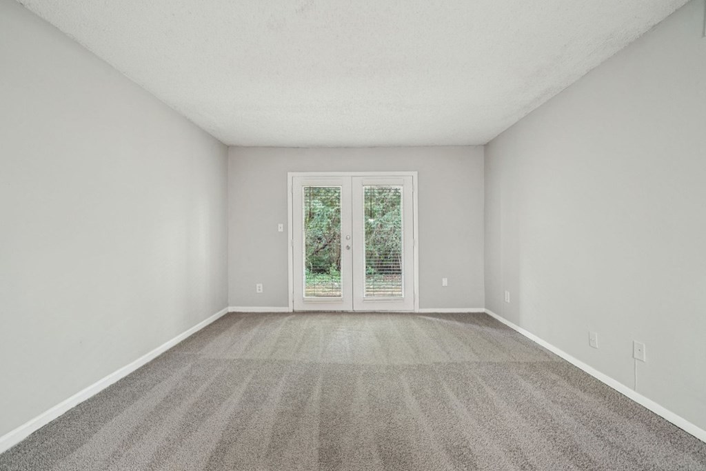 A room with a carpeted floor and a sliding glass door leading outside.at Hills at Hoover Apartments, Hoover, AL 35216