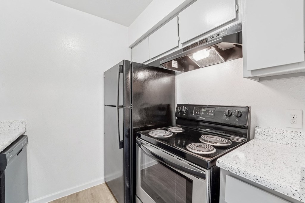 A black stove and refrigerator in a kitchen.