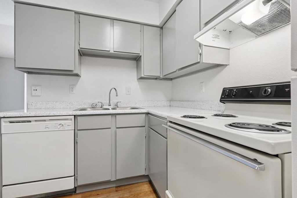 A white kitchen with a stove top oven and a dishwasher.