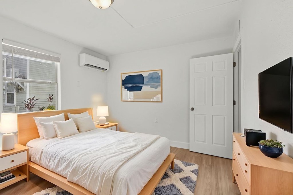 A bedroom with a bed, nightstands, and a painting on the wall.