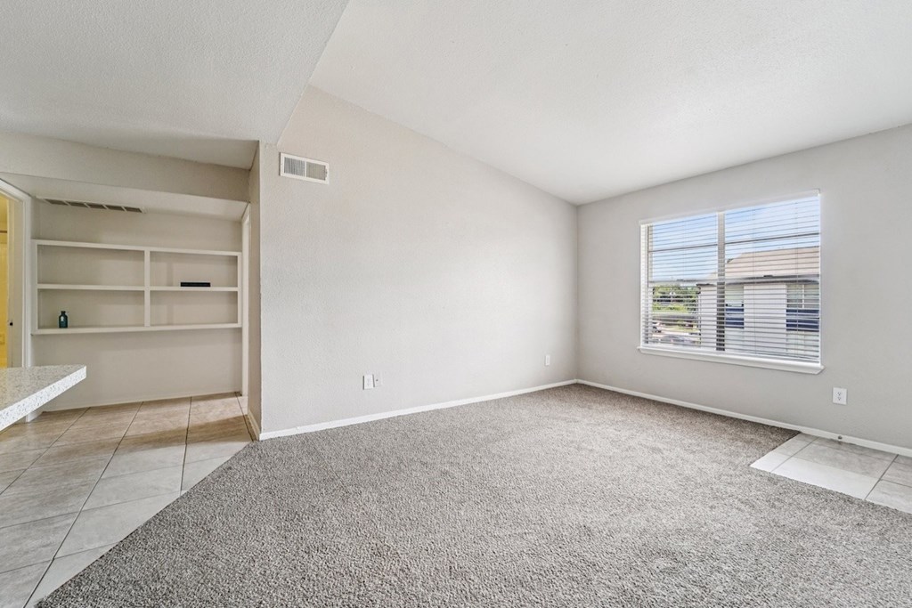 A room with a carpeted floor and a window with blinds.