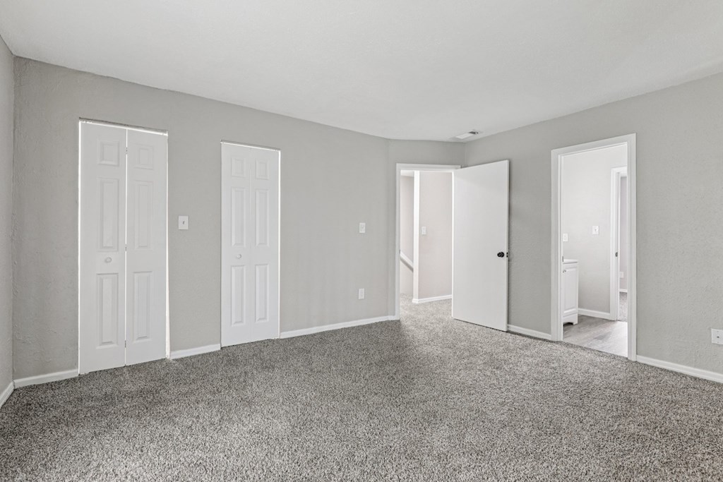 A room with grey carpet and white doors.