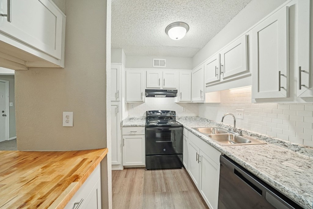 A kitchen with a wooden counter top and white cabinets.at Hills at Hoover Apartments, Alabama