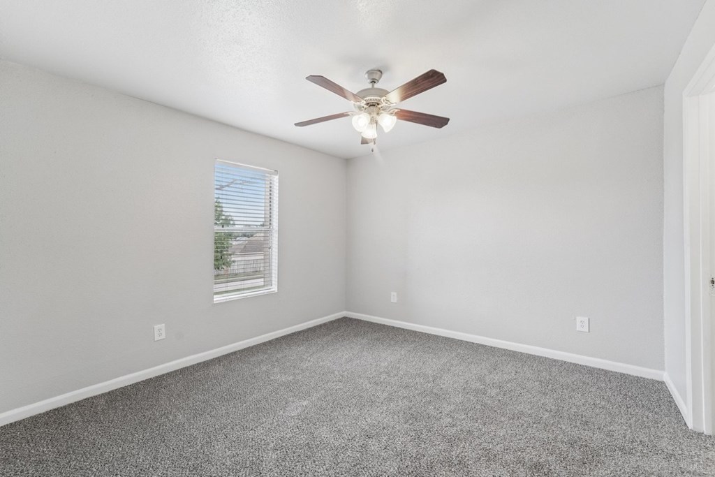 A room with a ceiling fan and carpeted floor.
