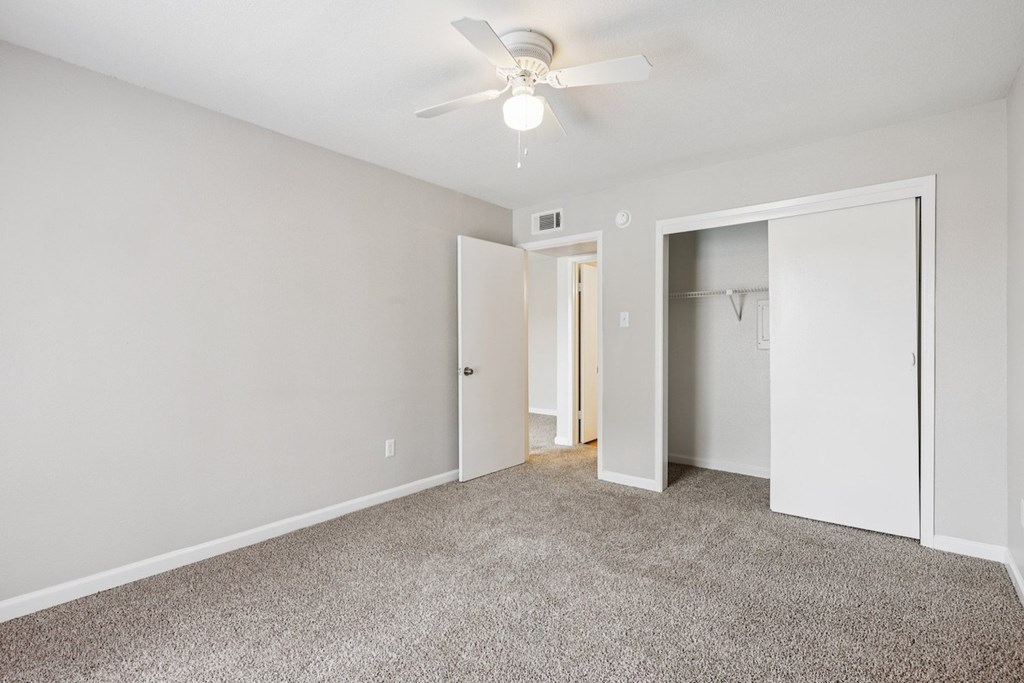 A room with a ceiling fan and carpeted floor.