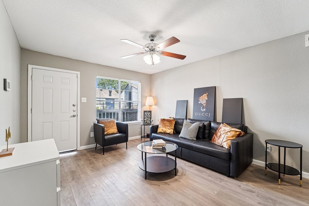 A living room with a black couch, a coffee table, and a ceiling fan.