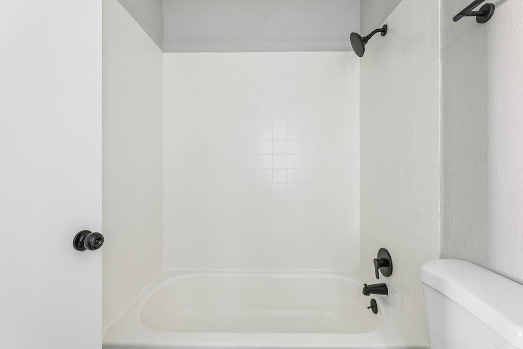 A white bathroom with a tub and a toilet.
