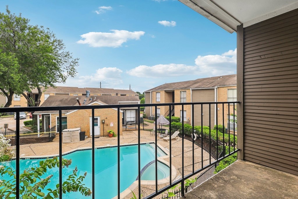 A pool in a backyard with a fence and houses in the background.