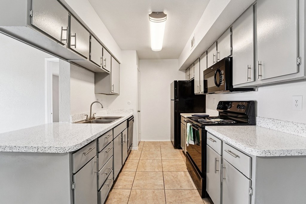 A kitchen with a white counter top and black appliances.